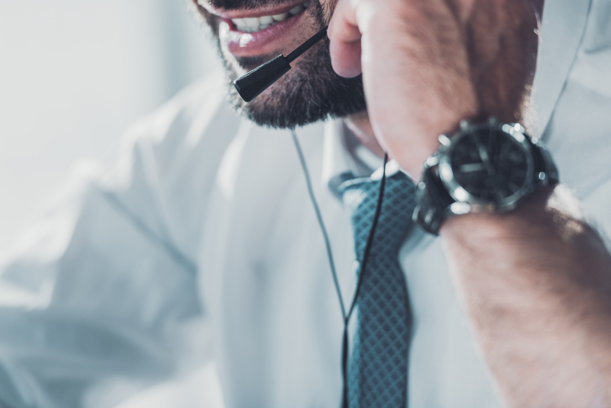 cropped shot of support hotline worker in shirt with tie talking by headphones with microphone